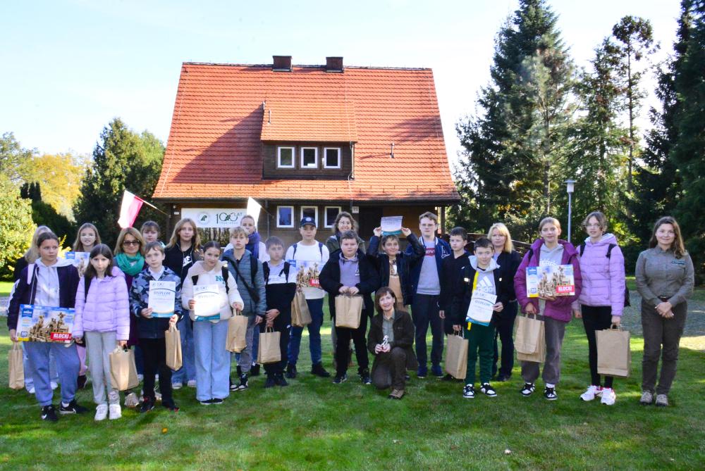 Uczestnicy&#x20;konkursu&#x20;&#x22;Poznajemy&#x20;las&#x22;&#x20;wraz&#x20;z&#x20;nauczycielami&#x20;i&#x20;leśniczkami&#x20;przed&#x20;budynkiem&#x20;Ośrodka&#x20;Edukacji&#x20;Przyrodniczo-Leśnej&#x20;w&#x20;Jeziorach&#x20;Wysokich&#x2e;&#x20;W&#x20;tle&#x20;jubileuszowe&#x20;logo&#x20;z&#x20;okazji&#x20;100-lecia&#x20;Lasów&#x20;Państwowych&#x2f;&#x20;fot&#x2e;&#x20;Paweł&#x20;Mrowiński